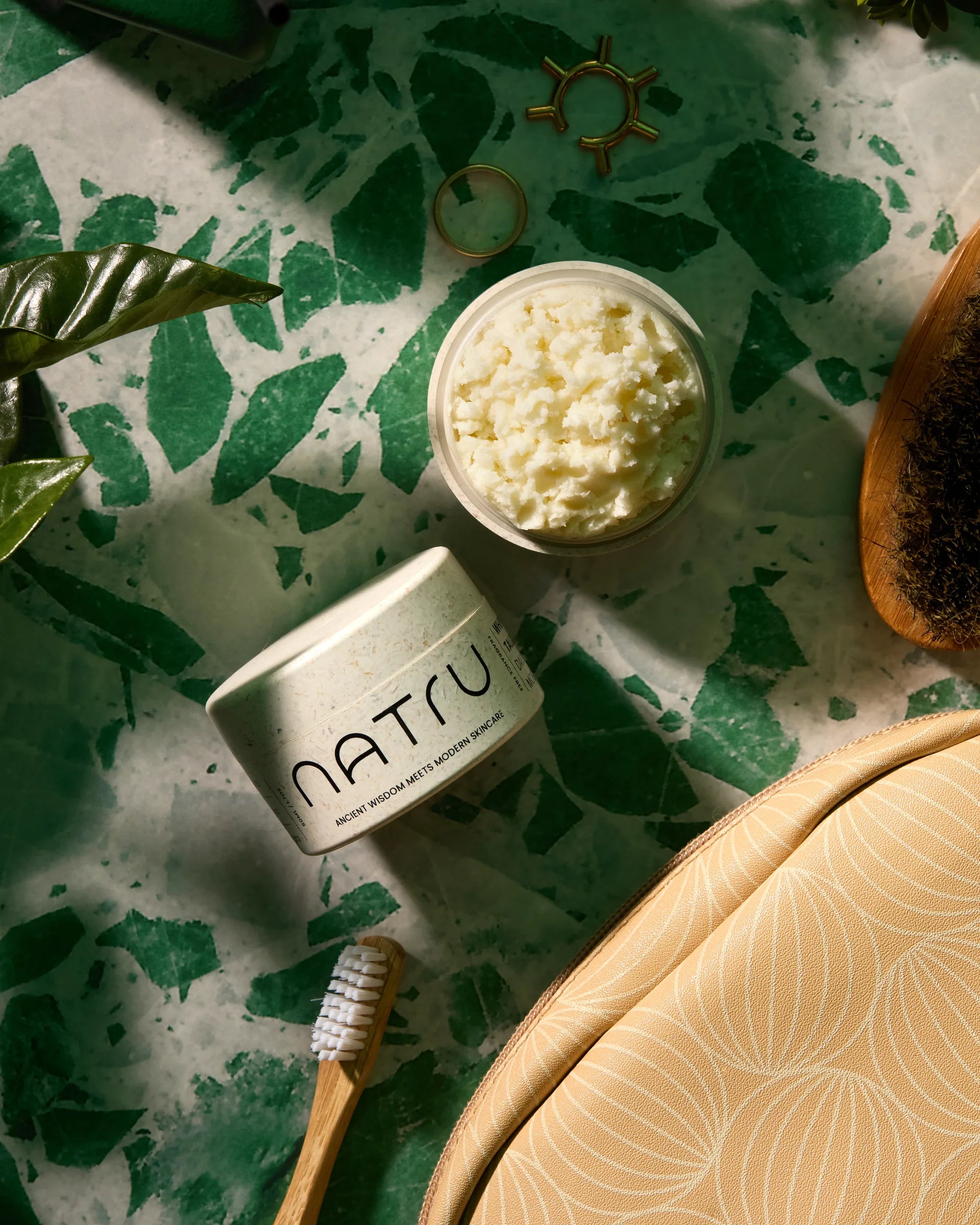 Natru jars in a flat lay with leaves, a brush, and a travel pouch