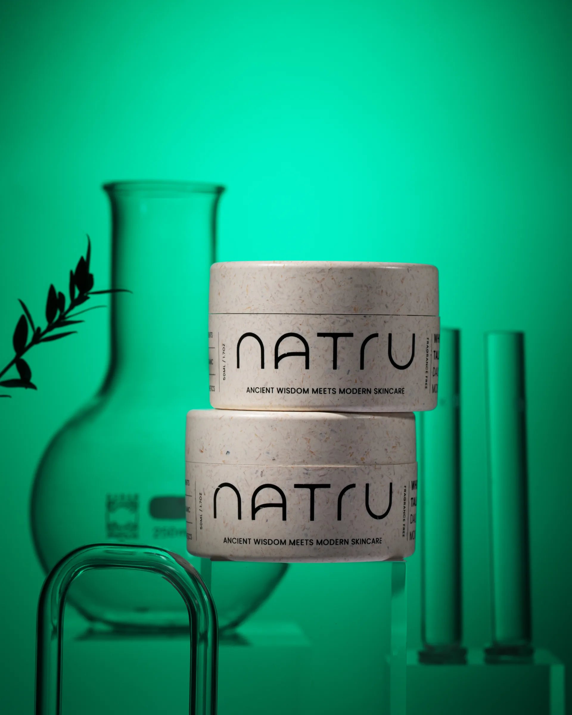 Two Natru jars stacked beside laboratory glassware on a green backdrop