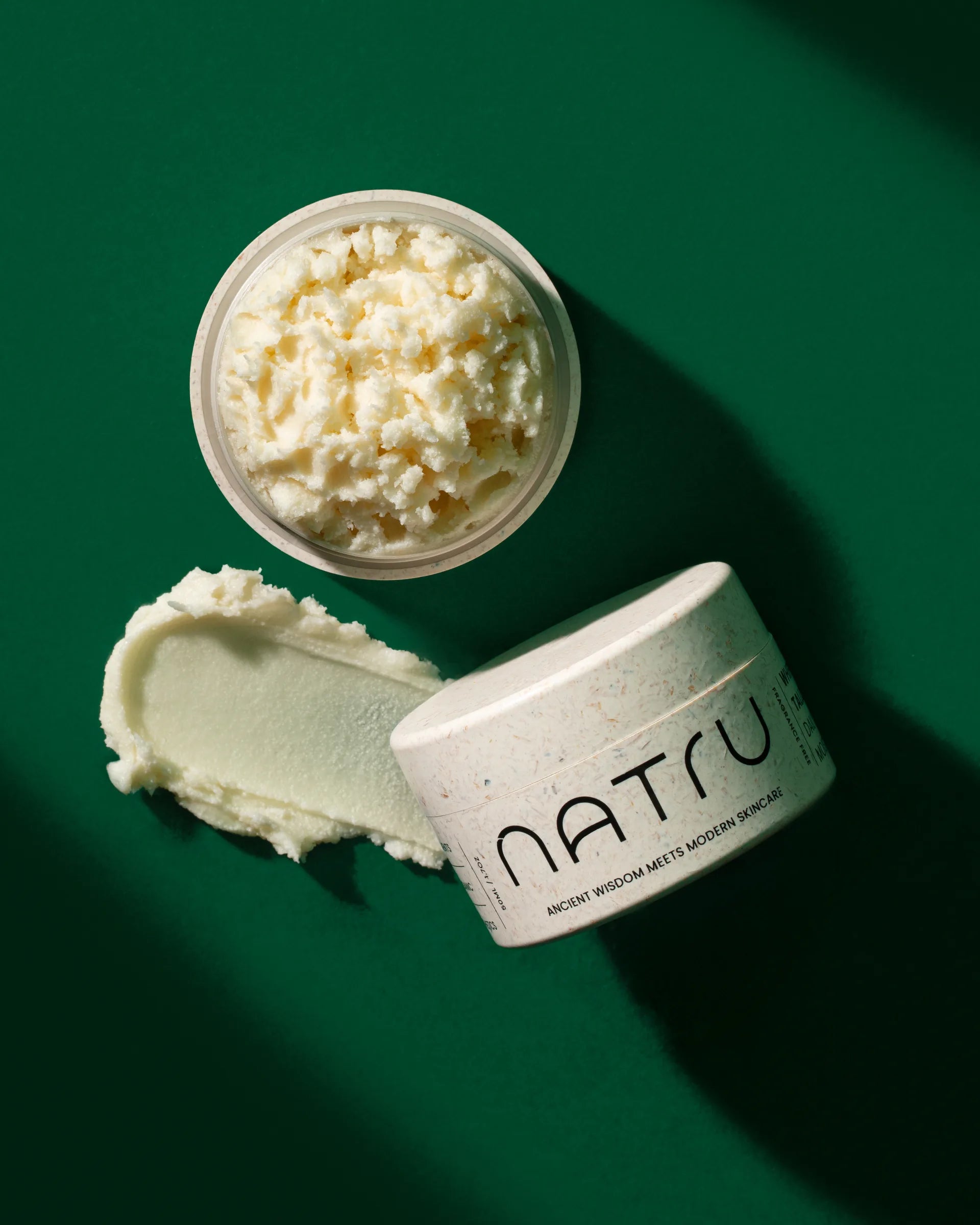 An open jar of Natru whipped tallow on deep green
