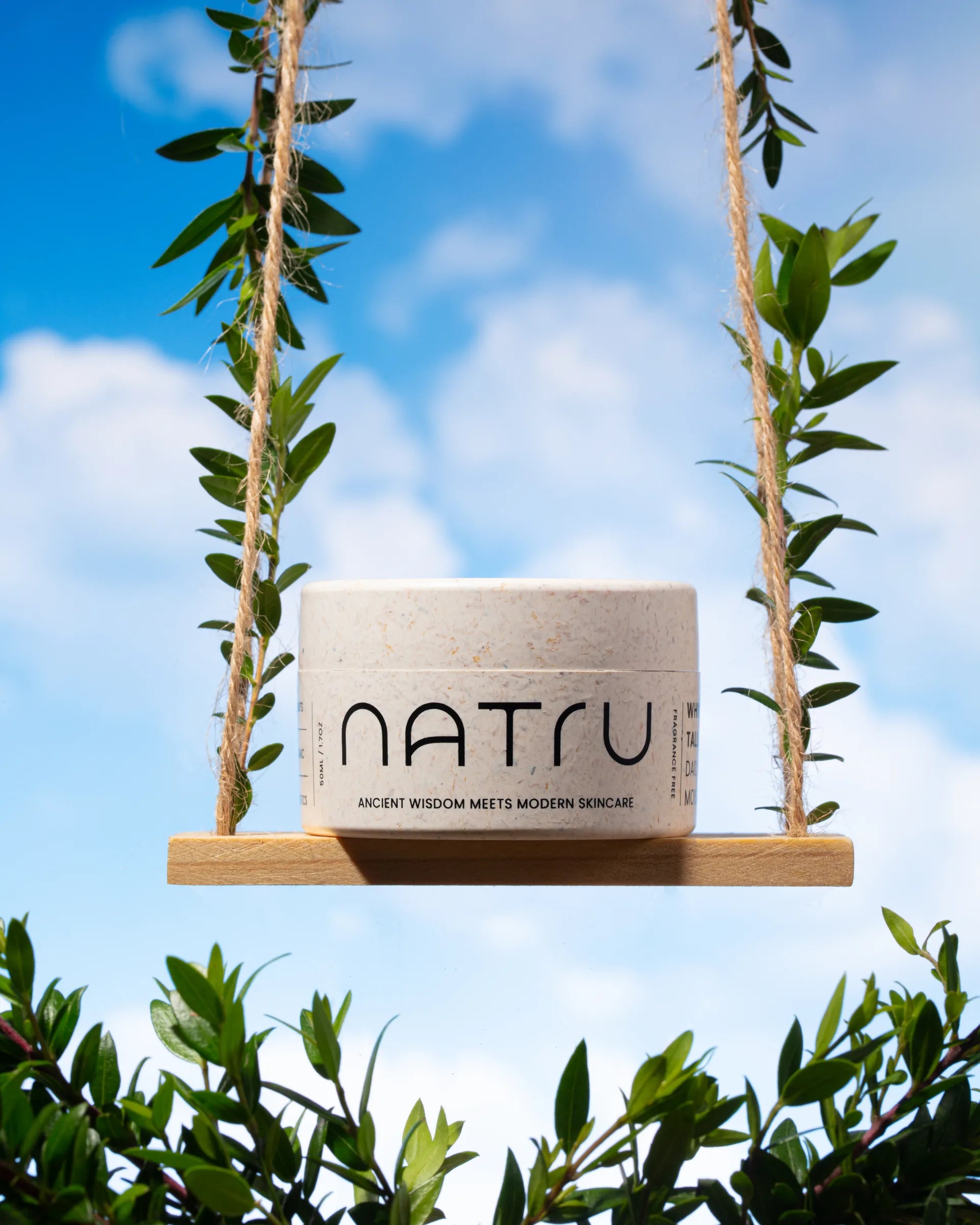 A Natru jar on a wooden swing hung with leafy vines against a blue sky